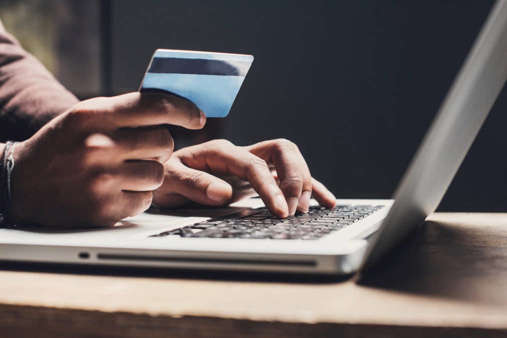 man holding credit card at computer