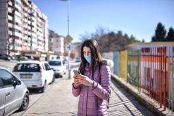 woman holding cell phone near apartment buildings