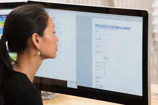 Photograph of a woman looking at a computer screen with a job application document open.