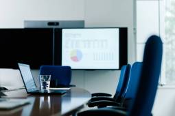 A photograph of an unattended conference table in a conference room with a video conference system.